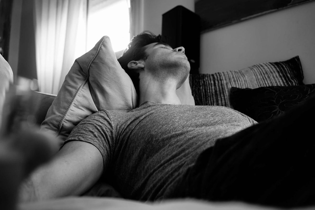 Person sover hevet opp mot puter i sengen