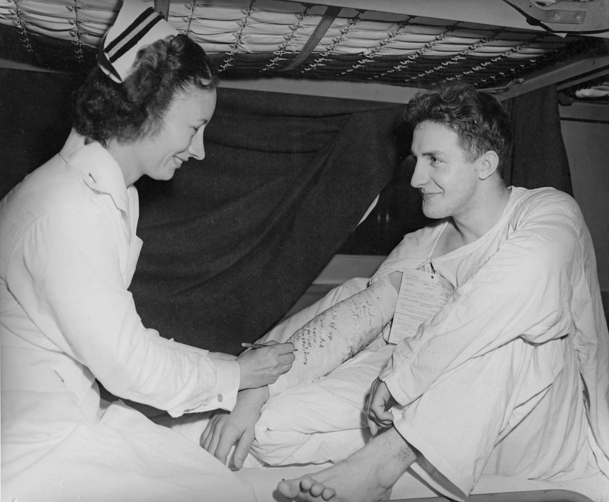 Historisk sort-hvitt foto av sykepleier som steller pasient i seng