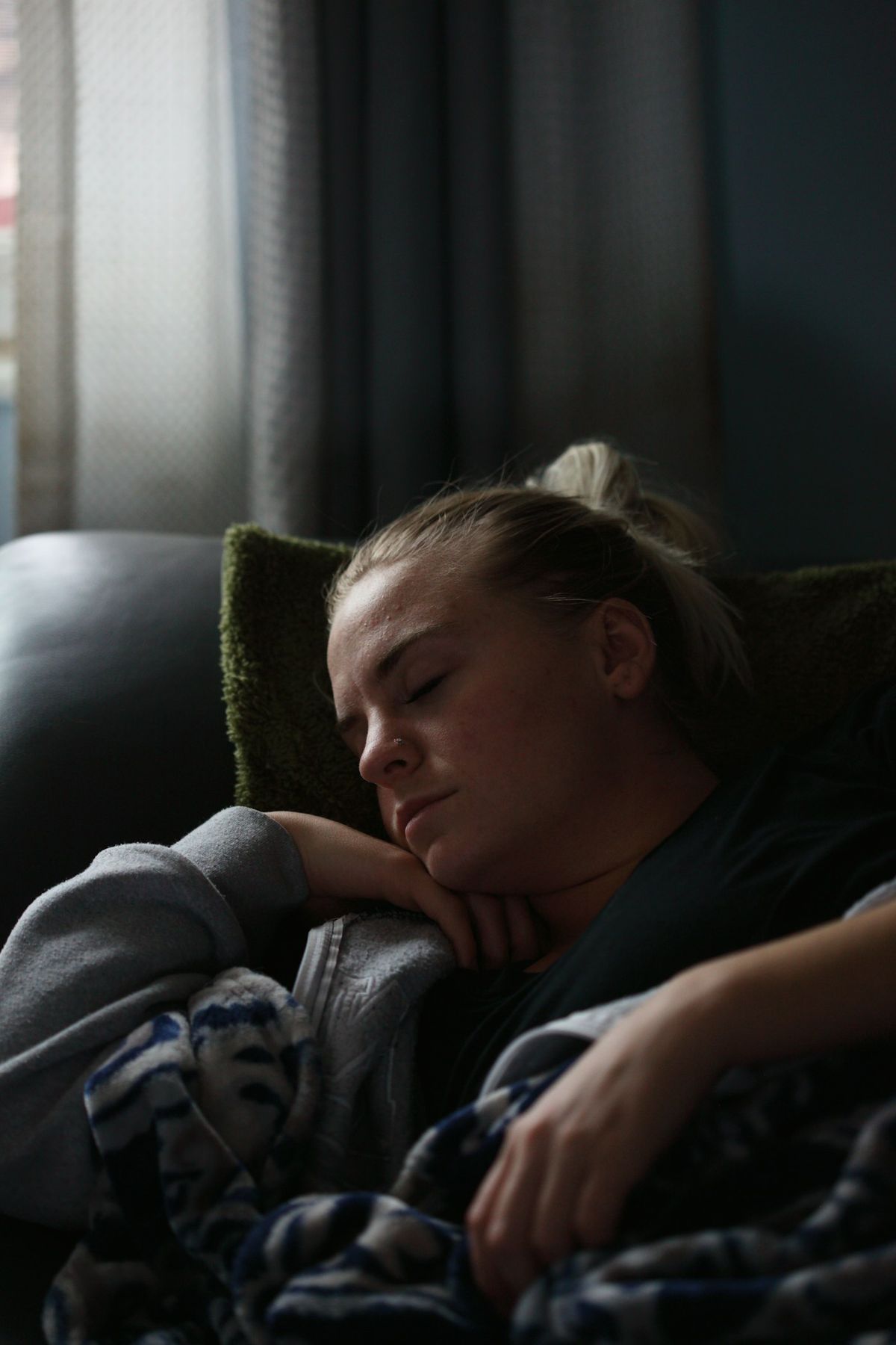 Trett person hviler under teppe i sofaen